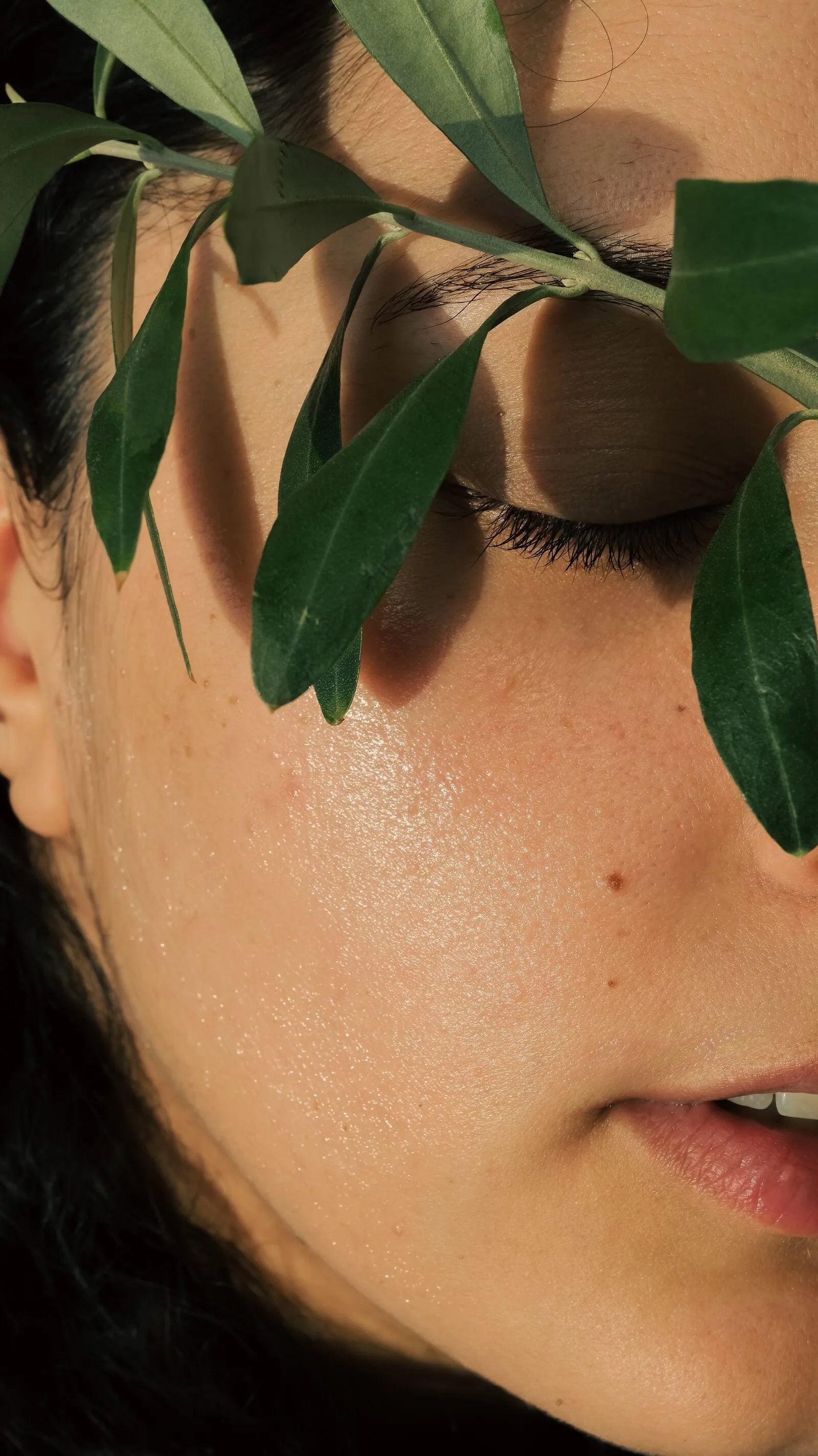 A woman with olive leaves resting across her face